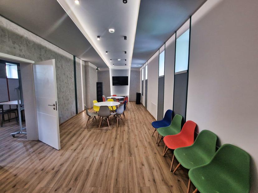 Przestronna sala edukacyjna z szafkami, stołami i kolorowymi krzesłami